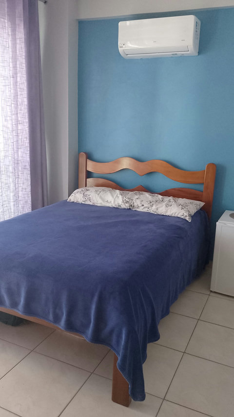 Quarto com cama de casal, frigobar eletrolux, ar condcionado split e cortina.