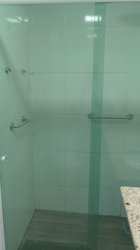 Banheiro social com 2 alças de apoio dentro do box para idosos.