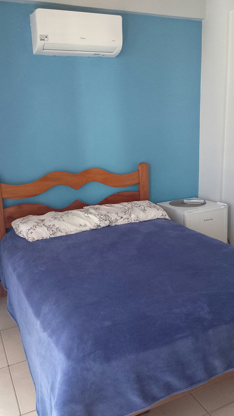Quarto com cama de casal, frigobar eletrolux, ar condcionado split e cortina.