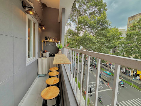 The balcony featuring a bar table with high chairs, perfect for dining outside while enjoying an amazing panoramic view. The seating offers a unique perspective of the bustling street below, creating an inviting spot for relaxation and socializing