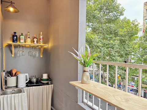 Scenic balcony near Bui Vien, offering a refreshing view of green trees, ideal for enjoying morning coffee or evening relaxation. The fully equipped kitchen area, complete with drinks and dining essentials, meets guests' expectations for the stay