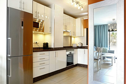 Modern culinary space with coffee machine, fridge, and all cooking essentials.