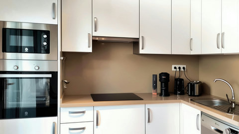 Sleek, fully equipped kitchen with oven, cooktop, dishwasher and coffee bar.