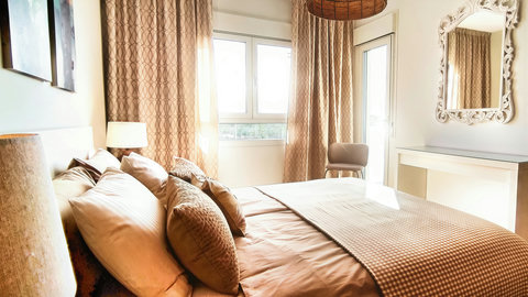 Sunny, serene bedroom with plush bedding and balcony access