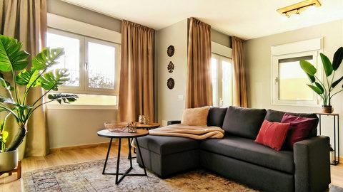 Bright, stylish lounge with sectional sofa, plants, and warm decor