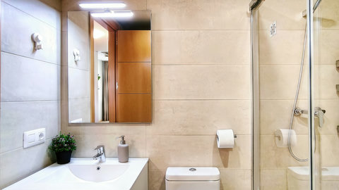 Bright modern bath with glass shower and lit mirror—spotless stay.