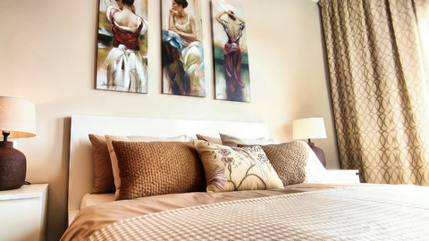 Stylish king bedroom with plush bedding, warm lighting, and chic art