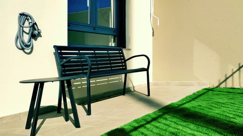 Sunny patio with modern bench, side table, and low‑maintenance turf.