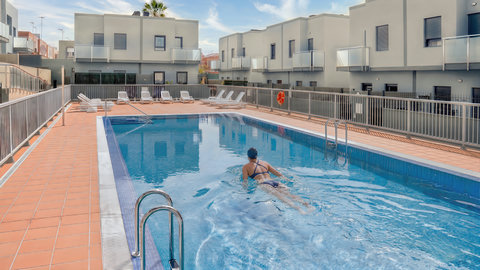 Spacious lap pool with sun loungers in a sleek, gated community