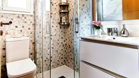 Modern bath with glass shower, mosaic tile, and bright floating vanity.
