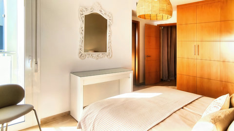Sunlit bedroom with balcony access, built-ins, and cozy bedding