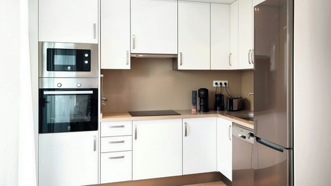 Sleek L-shaped kitchen with full appliances and a cozy coffee station