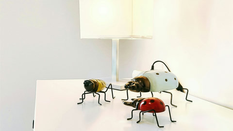 Modern side table with lamp and whimsical insect art accents.