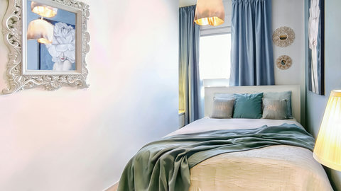 Bright, serene bedroom with cozy double bed, soft lighting, blue accents, and blackout curtains.