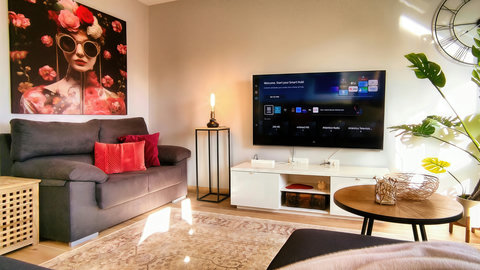 Sunny lounge with smart TV, plush sofa, chic art and greenery