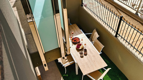 Sunny private balcony with dining for four, wine-ready for alfresco evenings.