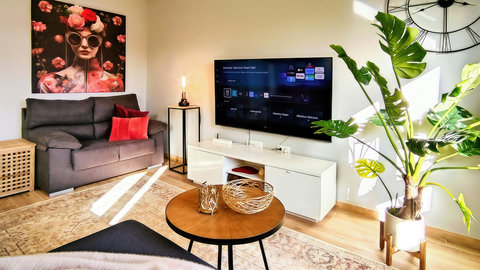 Sunny lounge with smart TV, chic decor & cozy loveseat retreat