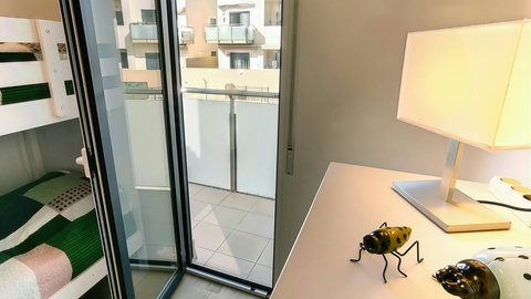 Sunny bunk room with balcony access and desk—perfect for families.