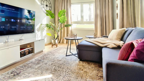 Bright lounge with smart TV, comfy chaise, big windows & chic decor