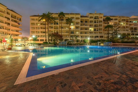 Resort-style pool oasis with palm trees, loungers, and evening glow