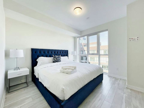 Elegant bedroom featuring a comfortable queen bed, modern décor, and large windows offering beautiful city views