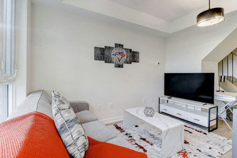 A bright, modern living room with cozy seating, smart TV, and elegant décor—perfect for relaxing after a day exploring Toronto. The sofa easily converts into a comfortable bed for extra guests.