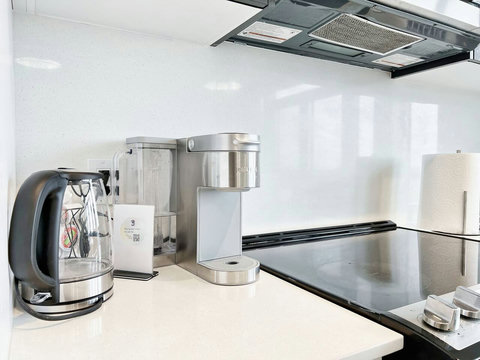 Modern full kitchen with stainless-steel appliances, coffee machine, dishwasher, and all essentials for home-style cooking. Perfect for preparing meals and enjoying family dinners together.