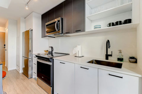 Modern full kitchen with stainless-steel appliances, coffee machine, dishwasher, and all essentials for home-style cooking. Perfect for preparing meals and enjoying family dinners together.