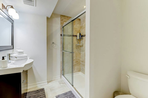 Modern elegance defined: a glass-door shower, floating glass shelves, and thoughtful touches of comfort