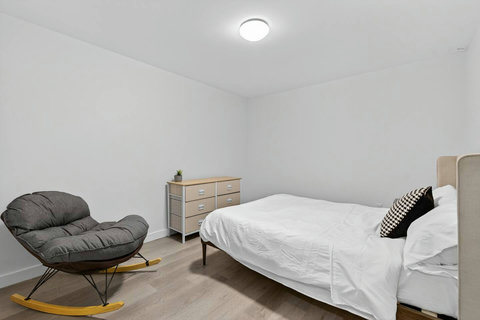Calming ensuite space with a neatly arranged chair and soft, ambient bedside light.