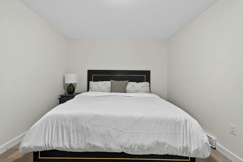 Simple, clean ensuite bedroom complete with a comfy chair and bedside lamp.