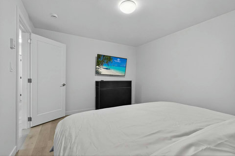 Cozy ensuite bedroom featuring a TV, comfortable chair, and soft bedside lighting