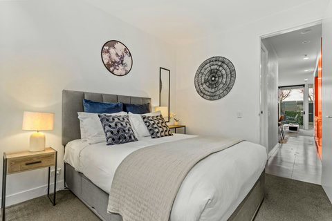 The Queen bed looks inviting with its crisp white sheets and pops of colour through cushions and artwork.