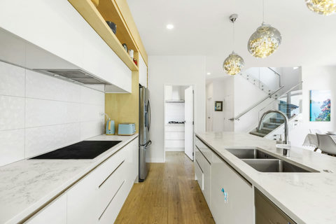 The kitchen has all the appliances you need, including double sinks, a cooktop, an oven, a microwave, and a dishwasher.