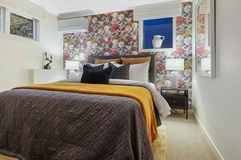 Bedroom 4 is located on the ground floor and has a distinct rose wallpaper and queen bed.
