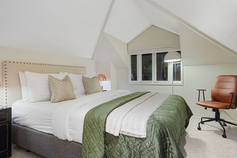 The master suite is located on the first floor and features a Queen bed with neutral colours and pops of green.