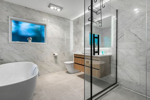 Plenty of space to get ready in this serene bathroom with great lighting and marble style tiles.