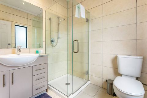 The ensuite bathroom has a glass shower, vanity and toilet.