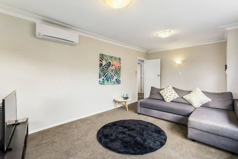 The large lounge space features a comfortable couch, an aircon unit for added comfort, and a wide-screen TV.