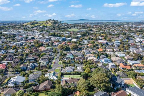 The house is centrally located, and Rangitoto Island is in the distance.