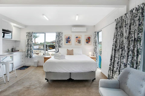 View of the studio unit encompassing the bed, kitchenette, dining table and chairs.