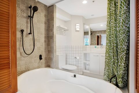The bathroom has a large bathtub, shower over bath, toilet and vanity unit.