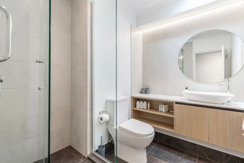 The bathroom has a glass shower, large vanity and toilet.