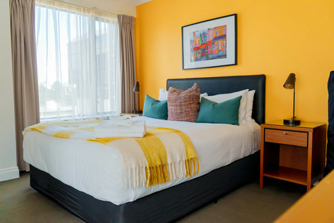 The Queen bed looks inviting with its crisp white sheets and pops of colour from the soft furnishings and artwork.