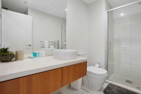 The bathroom has a glass shower, vanity unit, heated towel rail and toilet.