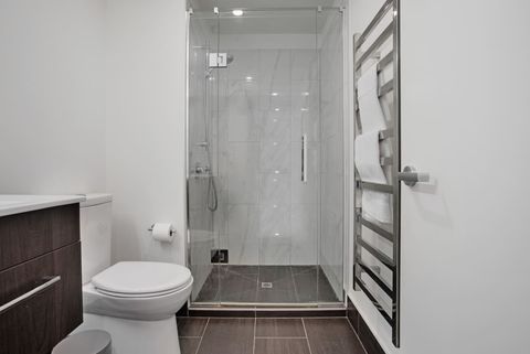 The bathroom has a glass shower, vanity and toilet.