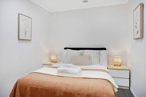 There are crisp white sheets and a colourful throw on this double-sized bed.