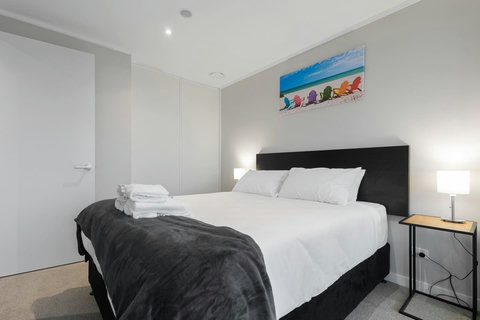 There are crisp white sheets and a fluffy throw on this Queen-sized bed.