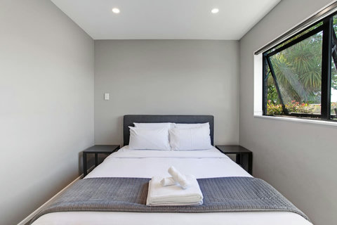 There are crisp white sheets and a grey throw on this Queen-sized bed.