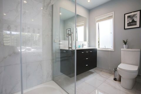 The ensuite bathroom has a shower, large double vanity unit and toilet.